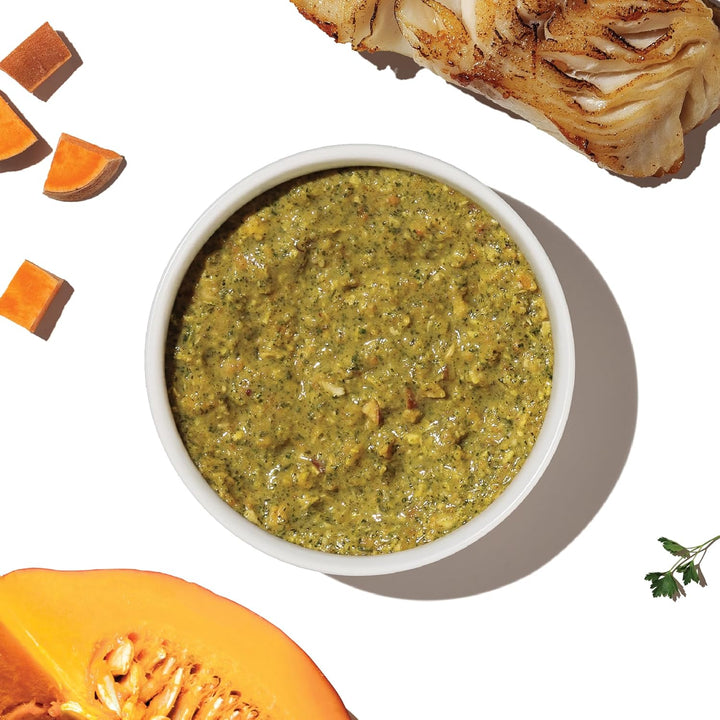 Bowl of green pesto with pumpkin pieces on a white background.Grain-Free Fish Recipe Dehydrated Dog Food