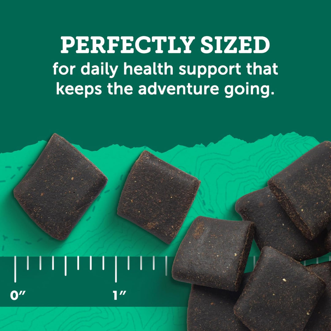 Dark-colored square-shaped items on a green background with text about daily health support. Zuke's Hip Action Hip & Joint Support 